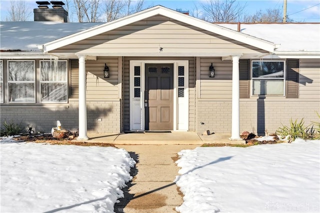 snow covered property entrance featuring covered porch