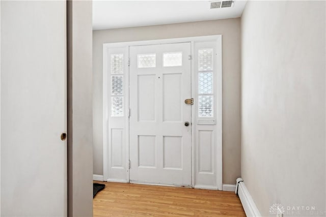 entryway with plenty of natural light, a baseboard radiator, and light wood-type flooring