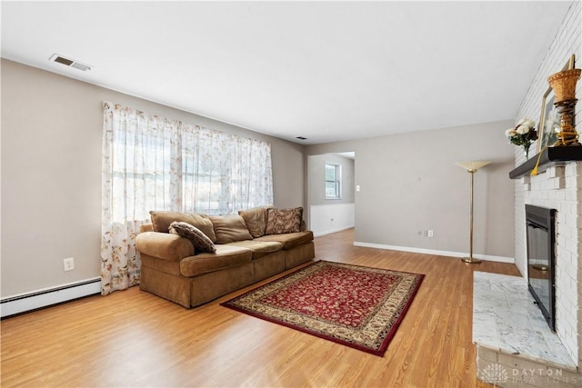 living room with hardwood / wood-style flooring, a healthy amount of sunlight, baseboard heating, and a fireplace