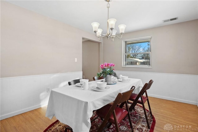 dining space featuring light wood-type flooring and an inviting chandelier