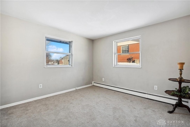 empty room featuring carpet flooring, baseboard heating, and a healthy amount of sunlight