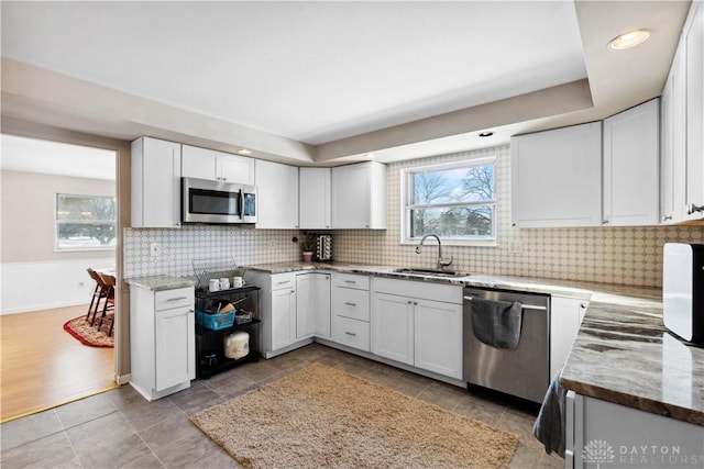 kitchen featuring light stone countertops, sink, light hardwood / wood-style floors, white cabinets, and appliances with stainless steel finishes