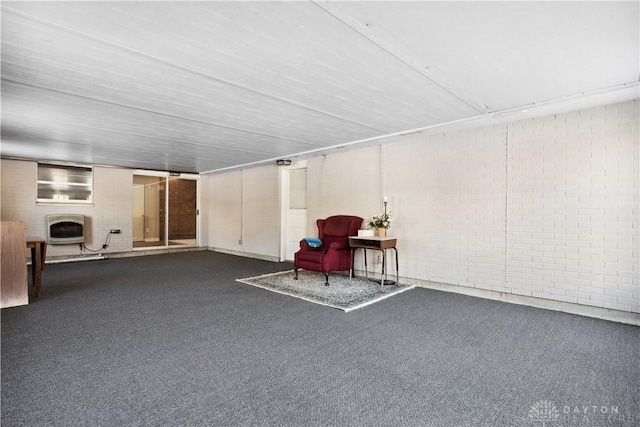 basement featuring a multi sided fireplace, heating unit, dark carpet, and brick wall