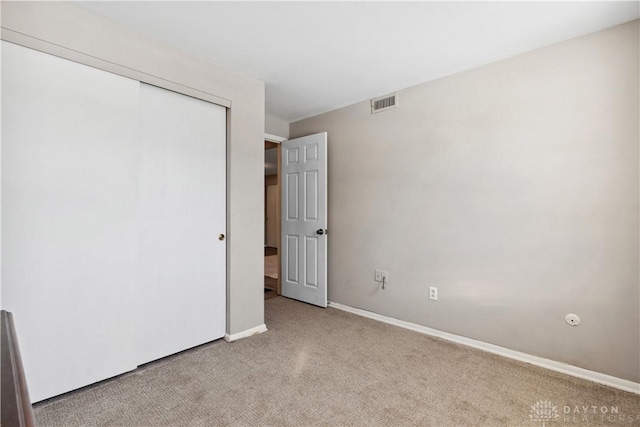 unfurnished bedroom with light carpet and a closet