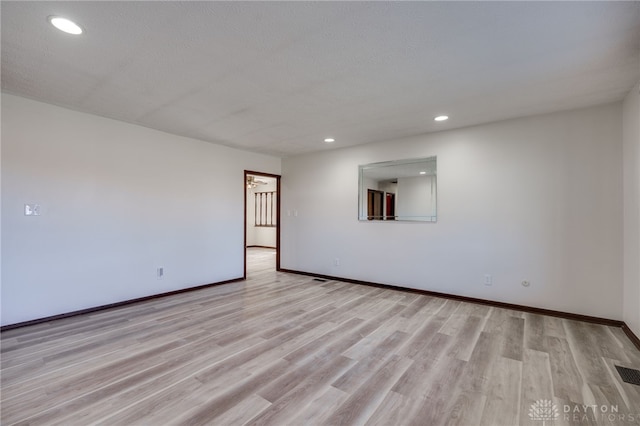 spare room with light hardwood / wood-style floors and a textured ceiling