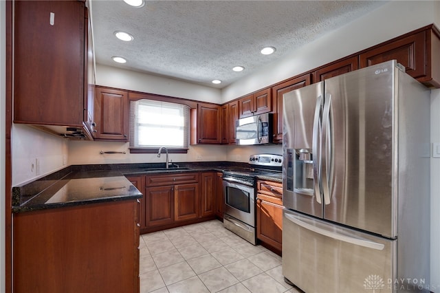 kitchen featuring sink, light tile patterned floors, a textured ceiling, and appliances with stainless steel finishes