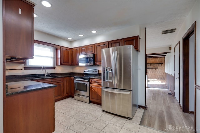 kitchen with sink, light tile patterned floors, stainless steel appliances, and a textured ceiling