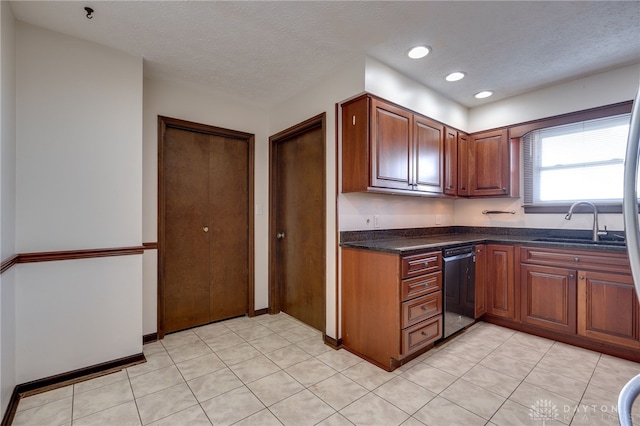 kitchen with dishwasher, sink, light tile patterned floors, and a textured ceiling