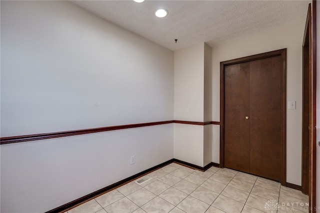 unfurnished bedroom featuring light tile patterned flooring, a textured ceiling, and a closet