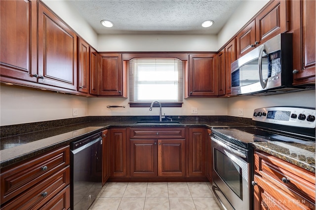 kitchen featuring sink, stainless steel appliances, dark stone countertops, a textured ceiling, and light tile patterned flooring