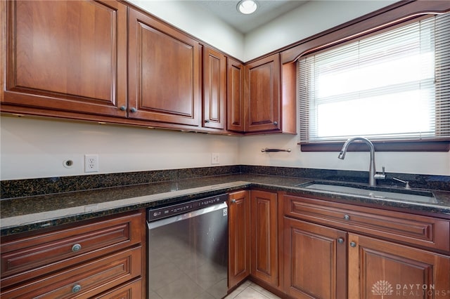 kitchen featuring dark stone countertops, dishwasher, light tile patterned flooring, and sink