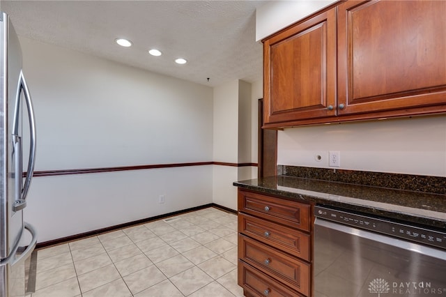 kitchen with dark stone countertops, light tile patterned floors, stainless steel appliances, and a textured ceiling