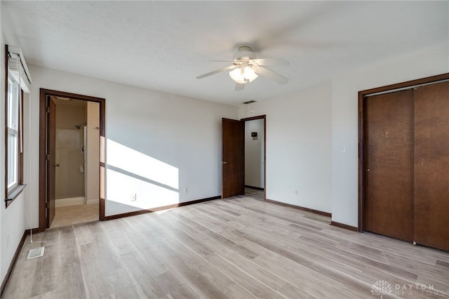 unfurnished bedroom with a textured ceiling, ceiling fan, light hardwood / wood-style flooring, connected bathroom, and a closet