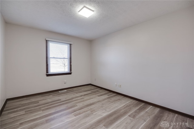 empty room featuring light hardwood / wood-style floors and a textured ceiling