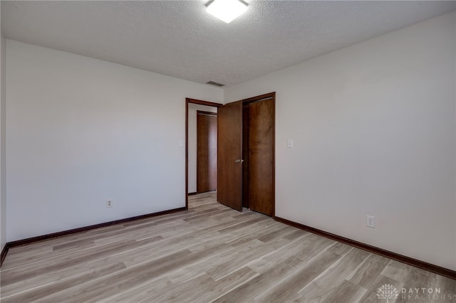 unfurnished room with light hardwood / wood-style floors and a textured ceiling