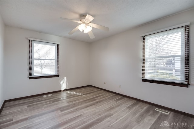 unfurnished room featuring a textured ceiling, light hardwood / wood-style floors, and ceiling fan