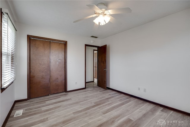 unfurnished bedroom with a closet, light hardwood / wood-style floors, and ceiling fan