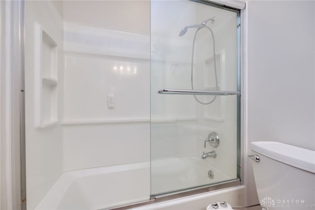 bathroom featuring enclosed tub / shower combo and toilet