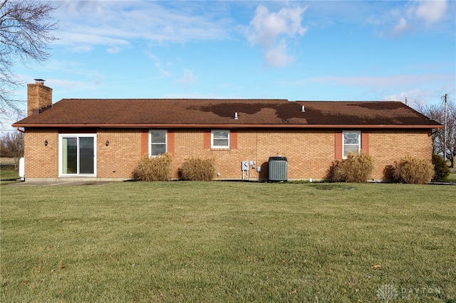 rear view of property with a lawn and cooling unit