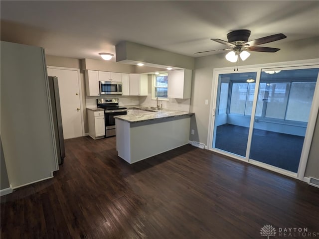 kitchen featuring kitchen peninsula, appliances with stainless steel finishes, dark hardwood / wood-style flooring, sink, and white cabinetry