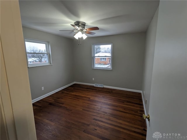 spare room with dark hardwood / wood-style flooring, ceiling fan, and plenty of natural light