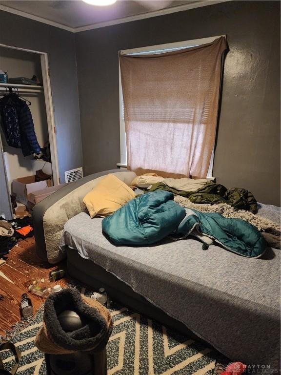 bedroom with hardwood / wood-style flooring, a closet, and ornamental molding