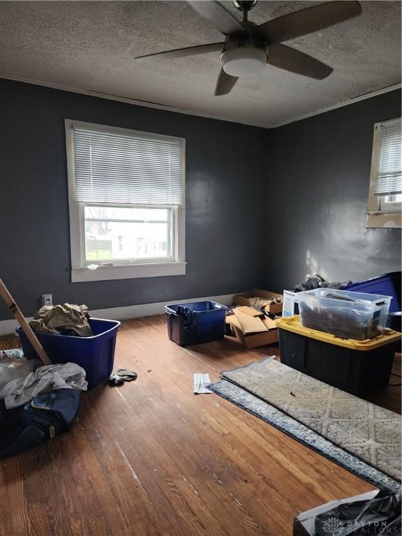 bedroom with ceiling fan, a textured ceiling, and hardwood / wood-style flooring