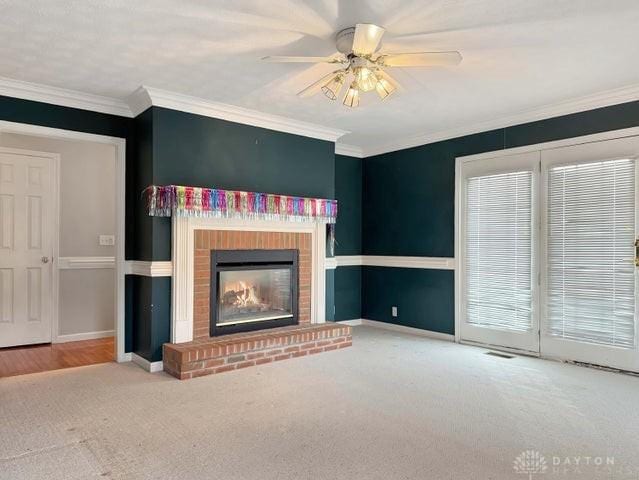 unfurnished living room featuring a brick fireplace, ceiling fan, carpet, and ornamental molding