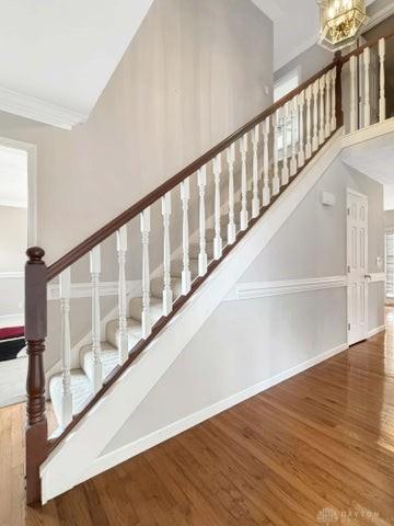 staircase with hardwood / wood-style floors, an inviting chandelier, and crown molding