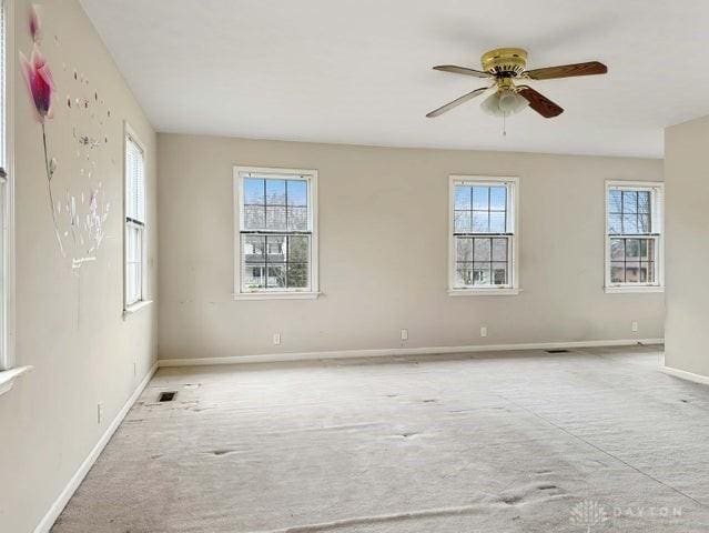 carpeted spare room with ceiling fan and plenty of natural light