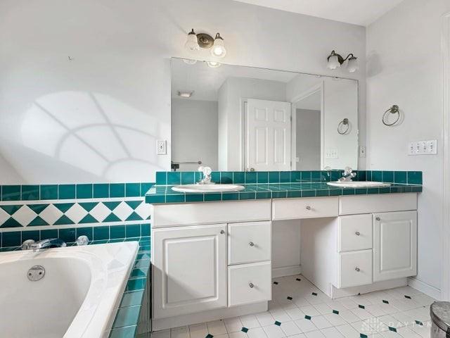 bathroom with tile patterned flooring, vanity, and a relaxing tiled tub