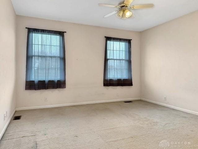 empty room with ceiling fan, plenty of natural light, and carpet