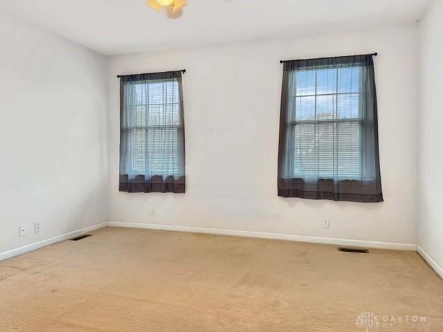 carpeted spare room with ceiling fan and plenty of natural light