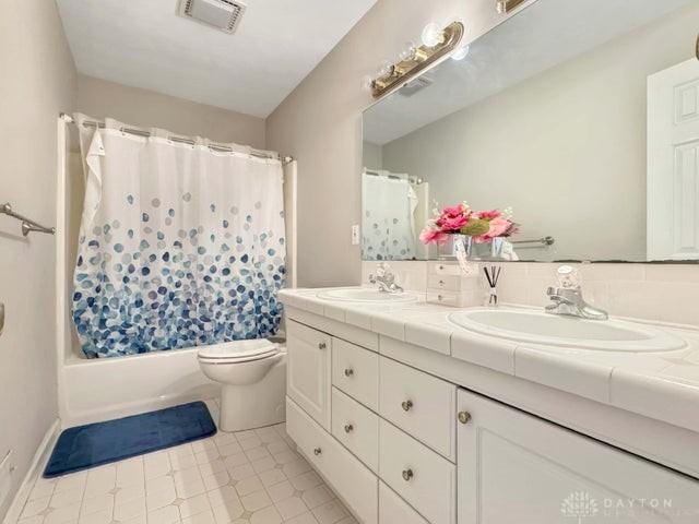 full bathroom with tile patterned flooring, vanity, shower / bath combo, and toilet