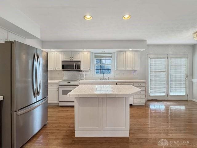 kitchen featuring tile countertops, plenty of natural light, white cabinets, and stainless steel appliances