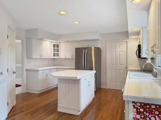 kitchen featuring white cabinets, tile counters, and wood-type flooring