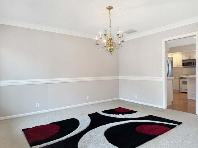 empty room with crown molding and an inviting chandelier