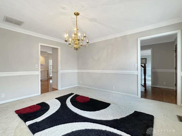 spare room with carpet flooring, ornamental molding, and a notable chandelier