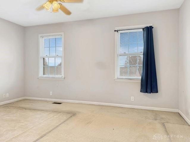 carpeted spare room featuring plenty of natural light and ceiling fan