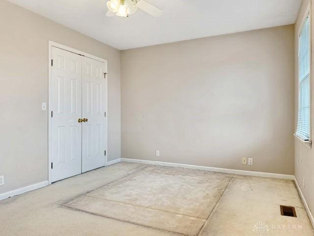 unfurnished bedroom with ceiling fan and a closet