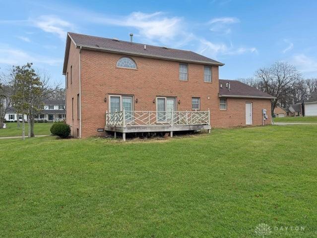 back of property with a wooden deck and a lawn