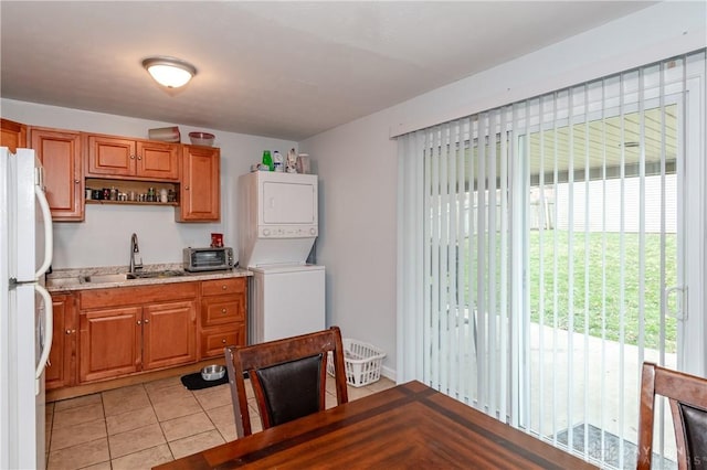 kitchen with plenty of natural light, white refrigerator, stacked washer / dryer, and sink