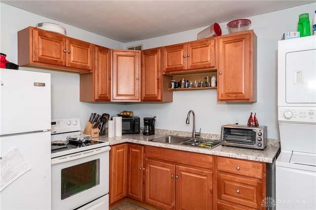 kitchen featuring stacked washer and dryer, white appliances, and sink