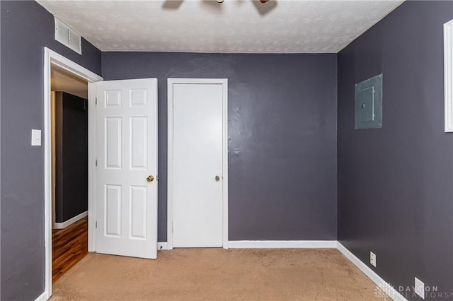 unfurnished bedroom with carpet flooring, a textured ceiling, and electric panel