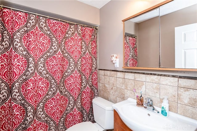 bathroom featuring vanity, toilet, and tile walls