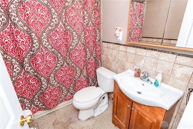 bathroom featuring tile patterned floors, vanity, toilet, and tile walls