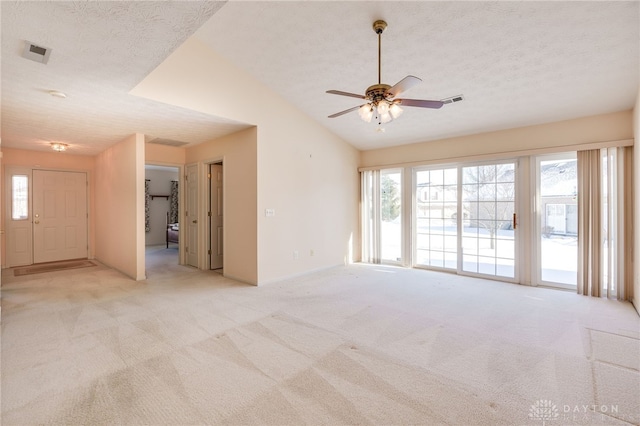 empty room with lofted ceiling, a textured ceiling, ceiling fan, and light carpet