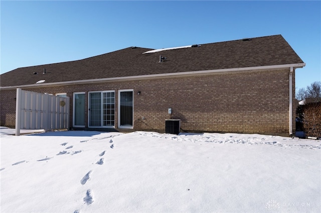 snow covered rear of property with central AC unit