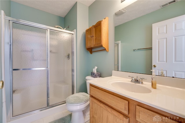 bathroom with a textured ceiling, tile patterned flooring, toilet, walk in shower, and vanity