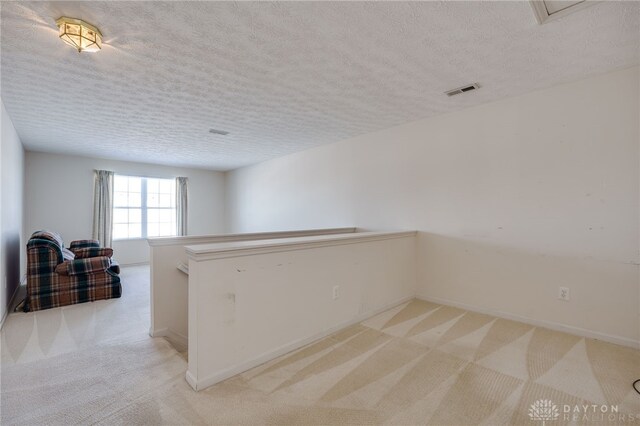 carpeted empty room featuring a textured ceiling